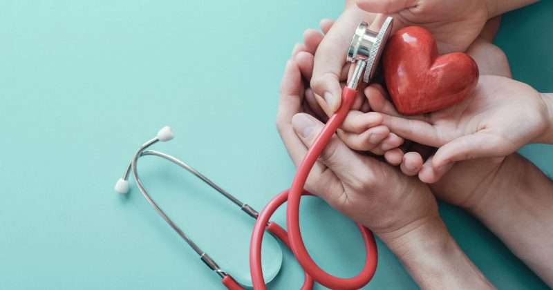 Family hands holding red heart with stethoscope, heart health,  health insurance concept, World heart day, world health day