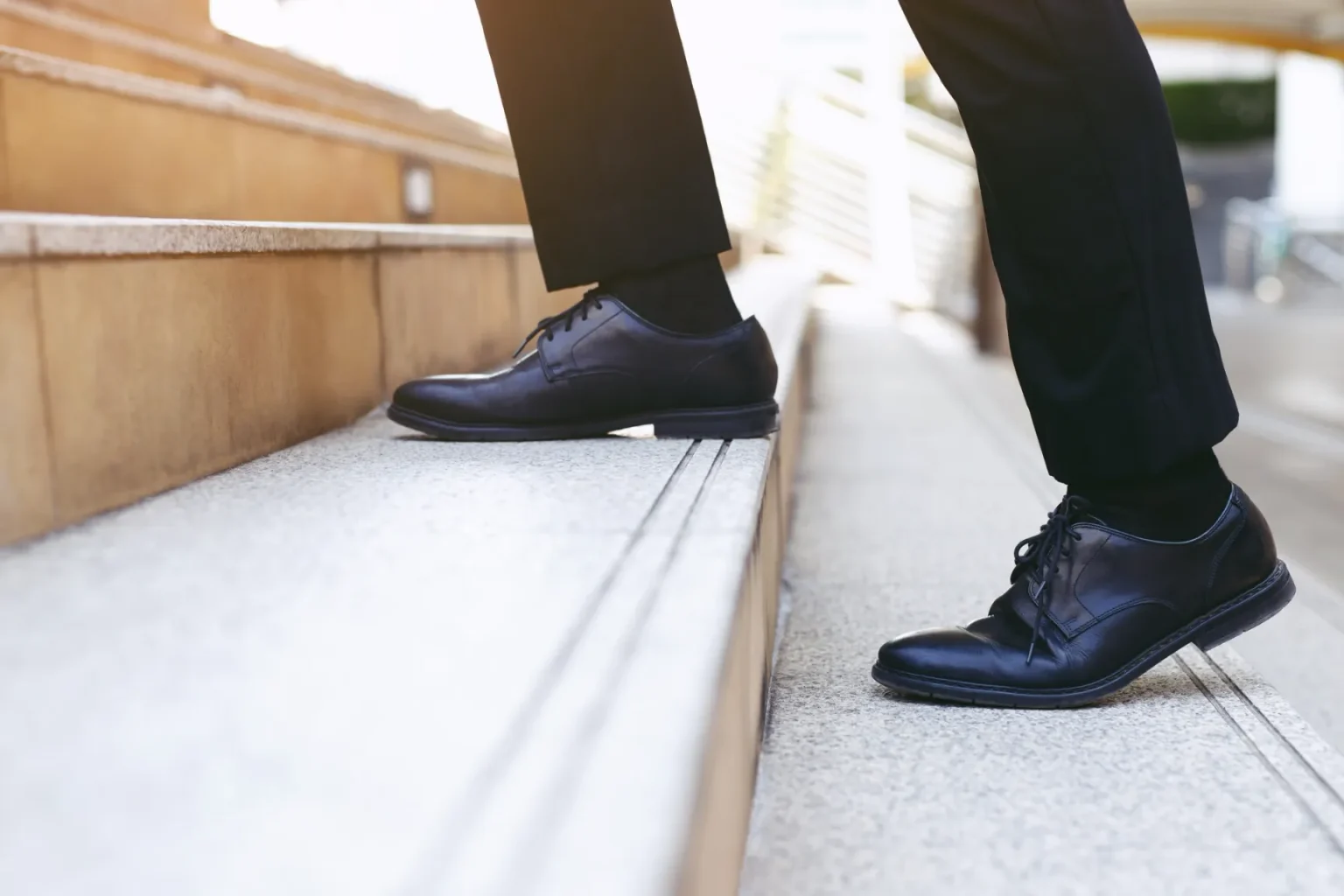 Man in business shoes taking first step on stairs