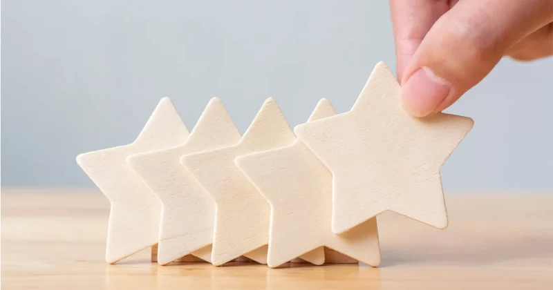 five wooden star blocks with hand placing fifth star block on table